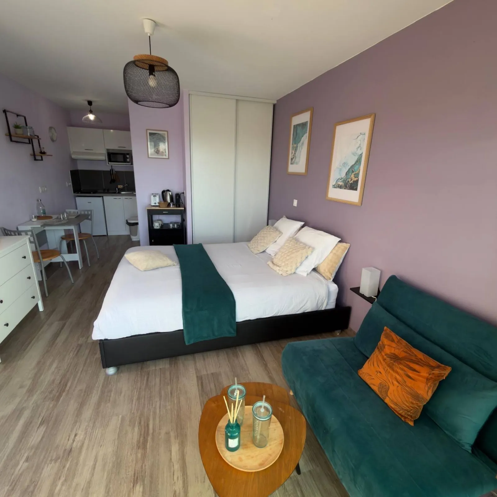 Studio aux murs mauves : lit double, canapé et coin cuisine